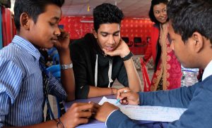 Neljä nepalilaista nuorta pöydässä ryhmätyön äärellä, Taksvärkki kampanjan kuvitusta.