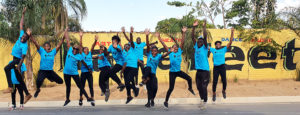 Sambialaisia nuoria hyppimässä iloisesti. Kaikilla ihmisillä on päällään sinisiset Barefeet-järjestön paidat.
