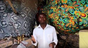 Nuori seisoo värikkäiden kankaiden välissä.