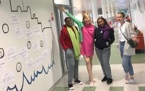 4 naista seisoo koulun käytävällä.