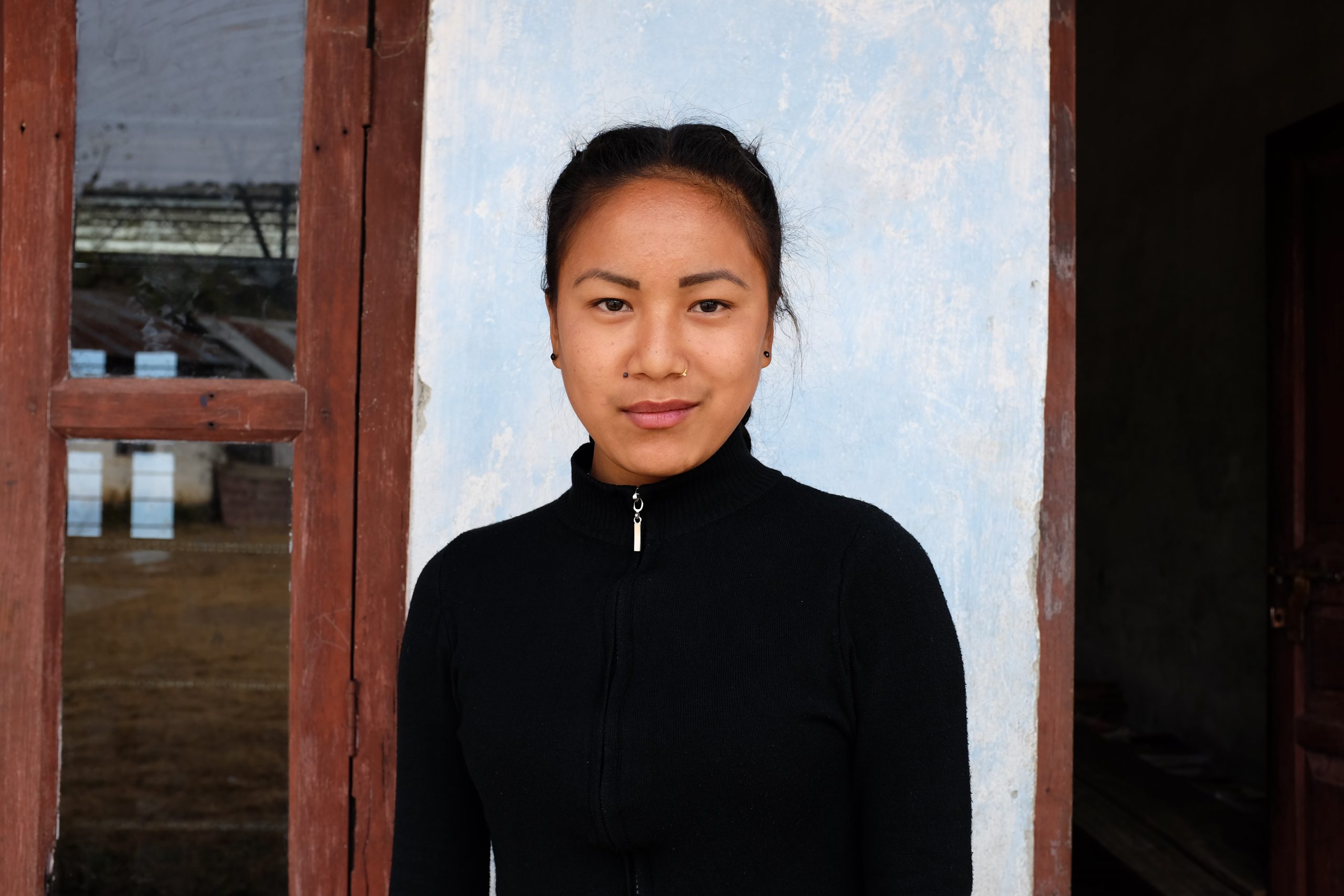 Nepalilainen tyttö koulun seinän edessä.