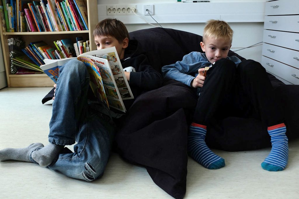 Kaksi poikaa lukemassa kirjoja lattialla.