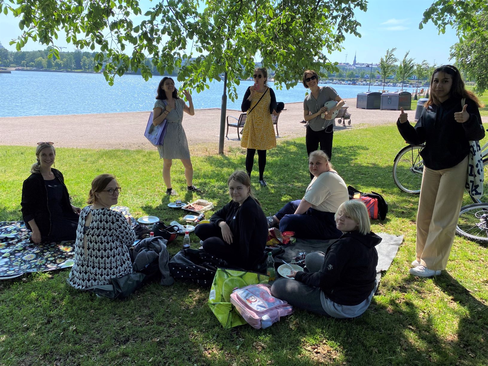 Ryhmä työntekijöitä ja nuoria piknikillä puistossa.