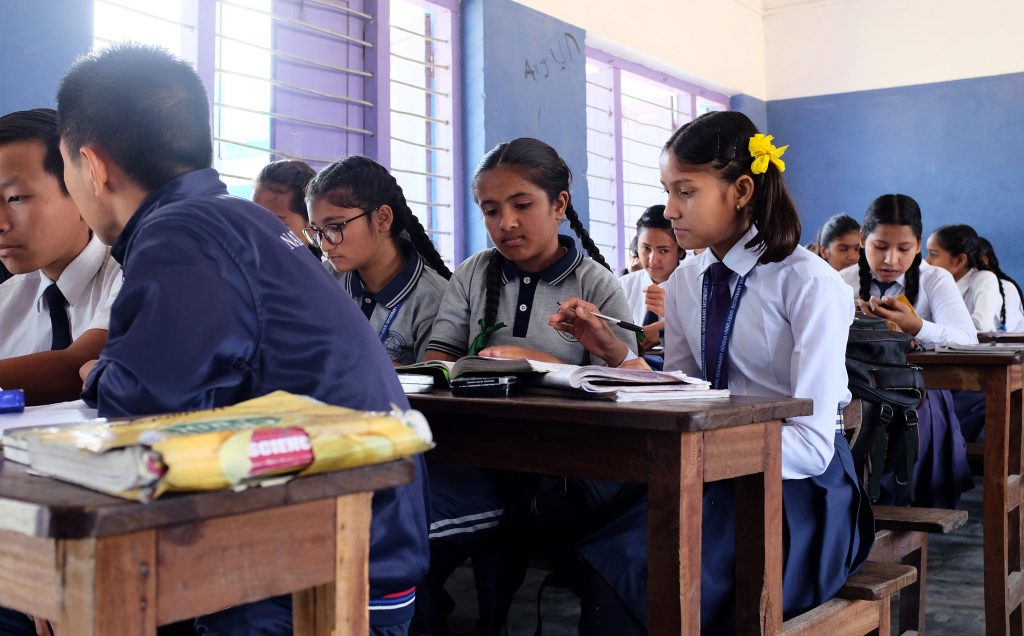 Luokkahuone Nepalissa pulpeteissa istuu koulupukuisia tyttöjä ja poikia.