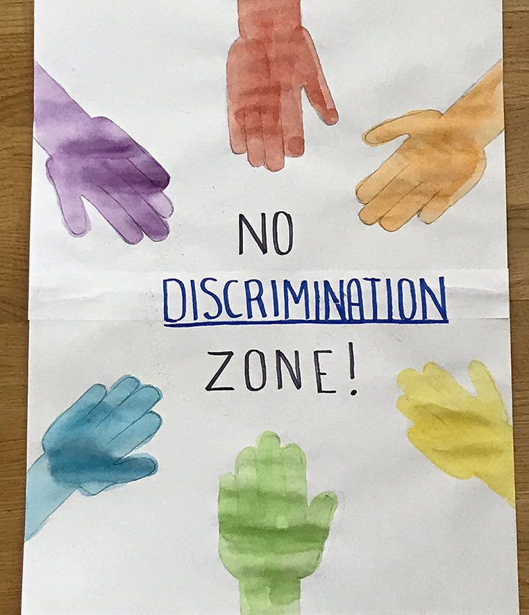 Vesiväreillä maalatut 6 eriväristä kättä ja keskellä teksti No discrimination zone eli Syrjinnästä vapaa alue.