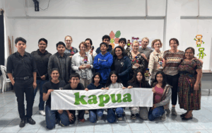 Ryhmäkuvassa 13 nuorta ja 8 naista. Eturivissä on 6 nuorta yksi polvi maassa ja pitelemässä valkoista kangasbanderollia, jossa lukee vihreällä kapua. Takarivissä loput ihmisistä seisovat lähekkäin. Kaikki katsovat kuvaajaa kohti ja hymyilevät.