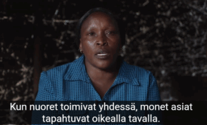 Kuvakaappaus videolta: sinipaitainen nainen puhuu ja katsoo kohti. Tekstityksessä lukee Kun nuoret toimivat yhdessä, monet asiat tapahtuvat oikealla tavalla.