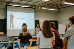 Kuusi henkilöä katsoo dialla olevaa väitettä seisten luokkahuoneessa.