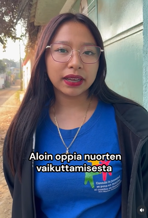 Nuori pitkähiuksinen nainen sinisessä paidassa ja mustassa takissa. Kuvan päällä teksti Aloin oppia nuorten vaikuttamisesta.