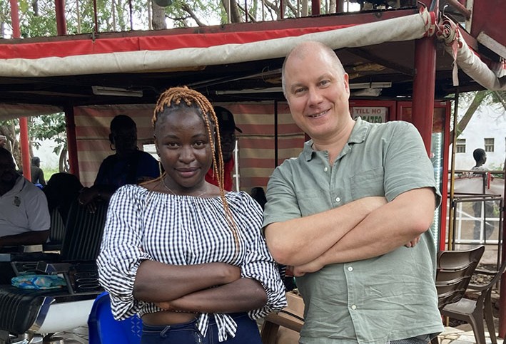 Kaksi ihmistä katsoo kameraa kohti hymyillen, kädet ristissä edessään.