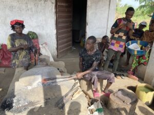 Kaksi ihmistä takoo metallitankoja, muutama ihminen seuraa sivussa.