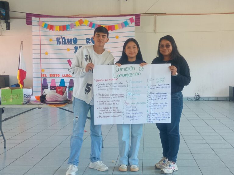 Kolme nuorta pitelee isoa paperia, jossa on kirjoitusta.